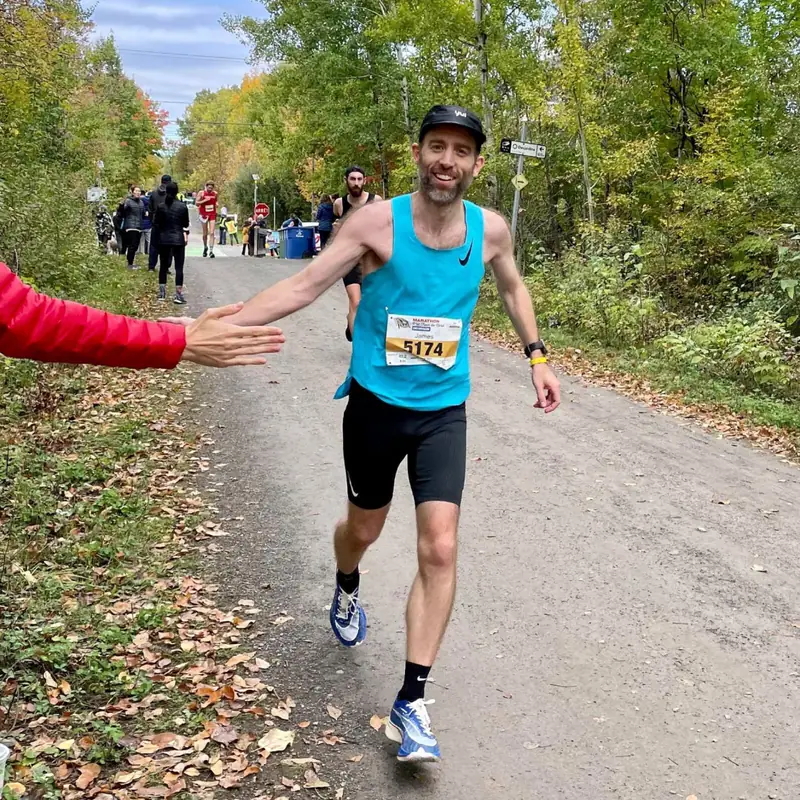 Jim McDannald high-fiving a spectator during the P'tit Train du Nord Marathon